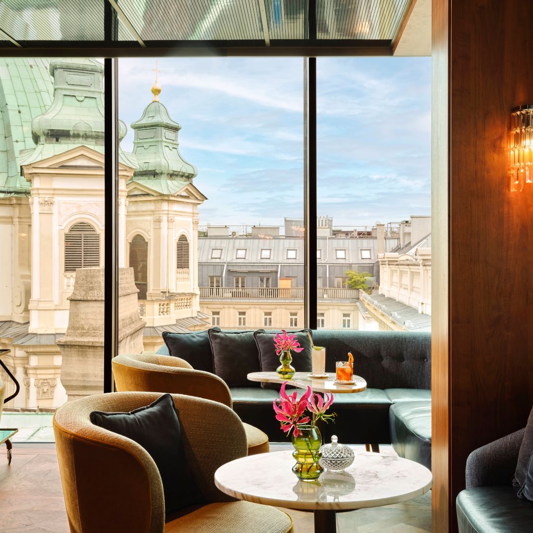 A rooftop restaurant in Vienna with a view of historic buildings through large windows.
